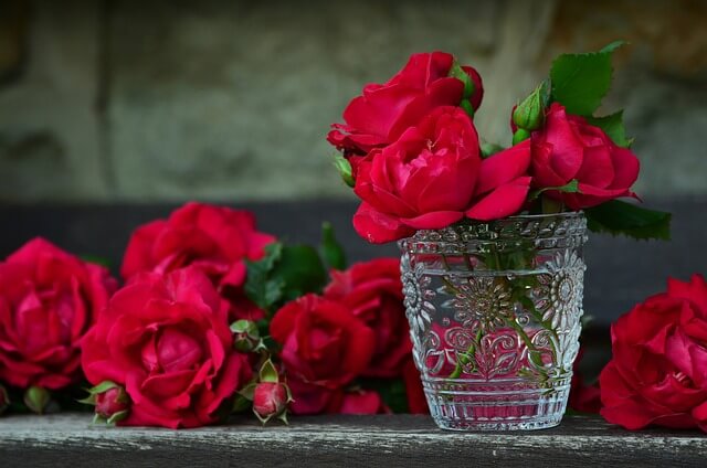 Red roses are placed in a jar and on the desk